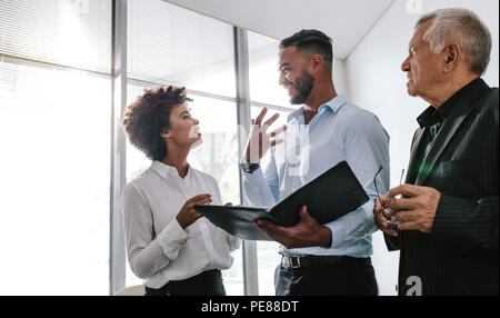 Ein Team aus drei Geschäftsleuten diskutiert über eine Akte in einem modernen Büro. Geschäftsleute, die über einen neuen Geschäftsplan sprechen. Stockfoto