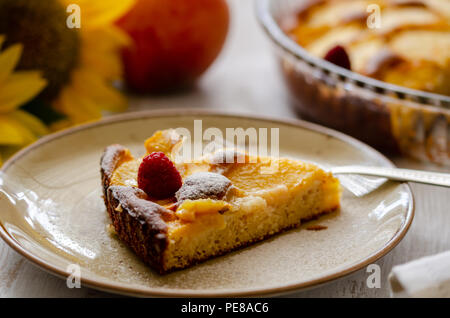 Stück hausgemachten Kuchen Pfirsiche auf einem Teller. Es gibt eine Himbeere und Pulver Zucker auf Pfirsichen pie selektiven Fokus. Stockfoto