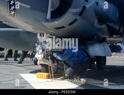 Ein Air Department Sailor sichert am 23. Oktober 2015 eine AV-8B Harrier auf dem Flugdeck des amphibischen Angriffsschiffs USS Boxer (LHD 4) während einer Composite Training Unit Exercise (COMPTUEX). Die Boxer Amphibious Ready Group, zu der USS New Orleans (LPD 18), USS Harpers Ferry (LSD 49) und die 13th Marine Expeditionary Unit gehören, führt szenariogesteuerte Übungen durch, um Schiffe und Marines durch Live-Schulungen zu integrieren, wobei der Schwerpunkt auf Einsatzbereitschaft und gemeinsamen Einsatzfähigkeiten liegt. Stockfoto