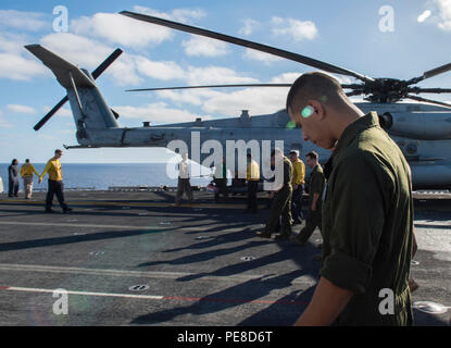 Sailors and Marines führen am 23. Oktober 2015 einen Rundgang über Fremdkörper (FOD) auf dem Flugdeck des amphibischen Angriffsschiffs USS Boxer (LHD 4) im Pazifischen Ozean durch. Die Boxer Amphibious Ready Group, einschließlich USS New Orleans (LPD 18), USS Harpers Ferry (LSD 49) und der 13th Marine Expeditionary Unit, führt eine Composite Training Unit Übung (COMPTUEX) durch, um die Einsatzbereitschaft, die Integration der Einheiten, die Szenarioreaktion, die Sicherheit des Flugdecks und die Koordination vor dem Einsatz zu testen. Stockfoto