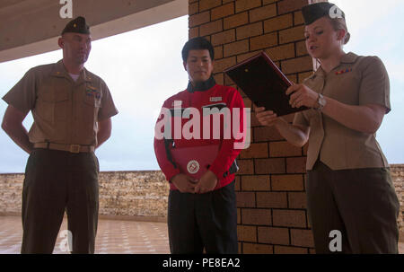 Ryuji Kishimoto, Mitte, erhält einen Brief der Wertschätzung von Leutnant Jennie Pearson, 23. Okt. 2015, bei Ie Shima, Okinawa, Japan, für selbstlos widmet seine Zeit gestrandet zu helfen Marines, Sept. 17, 2015. Marines mit Marine Wing Support Squadron-172, 1. Marine Flugzeugflügel, III Marine Expeditionary Force verloren, einen Reifen auf eine taktische Fahrzeug bei Reisen zu stützen. Kishimoto sah die Marines gestrandet und ergriff Maßnahmen durch die Bereitstellung von zwei 10-Tonnen-Buchsen und eine Luft-angetriebenen Werkzeug, um den Traktor zu reparieren. Kishimoto, ein Ie Shima Eingeborener, ist eine Tankstelle Mechaniker. Pearson, Eunice, New Mexiko Eingeborener, ist die Plat Stockfoto