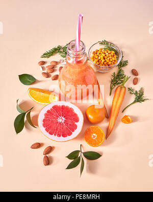 Frische saftige detox Smoothies im Glas Schale mit orangefarbenen Beeren, Gemüse, Früchte, Mandeln auf gelbem Papier Hintergrund. Ansicht von oben. Stockfoto