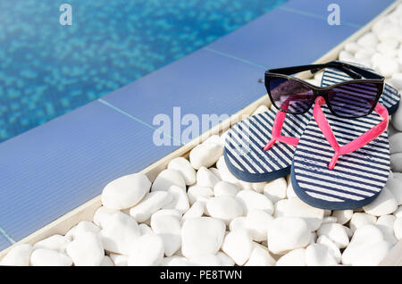 Flip-flops und Sonnenbrille am Pool. Close-up. Stockfoto