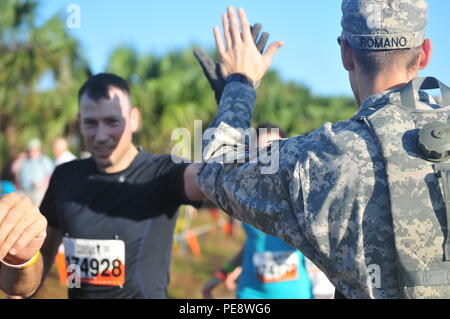 Spc. Rafaello Romano, mit dem 377. Theater Sustainment Command, High Fives eine haltbare Mudder Konkurrenten am Start der zentralen Florida harte Mudder in Palm Bay, Fla., Nov. 7. Die harten Mudder bringt Menschen zusammen in einer Reihe von Herausforderungen, denen sich die Teilnehmer nicht nur an ihre physischen Grenzen stößt, sondern testet auch Ihre geistigen Grit durch die Hindernisse zu erhalten. (U.S. Armee finden Foto von Sgt. Bethanien L. Huff) Stockfoto