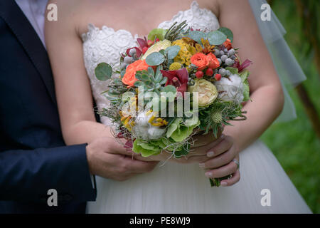 Kaukasische Paar mit Braut Holding eine große Herbst Blumen Blumenstrauß mit Sukkulenten und Beeren, ein farbenfrohes Accessoire für die Hochzeit Stockfoto