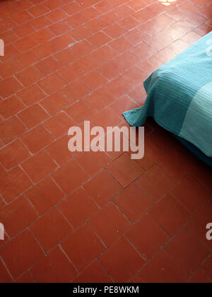 Rote Bodenplatten in ein Schlafzimmer mit einem großen französischen Dorf Haus, Ecke ein Bett von oben Stockfoto