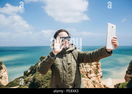 Eine junge Frau touristische oder Blogger kommuniziert über den Tablet-PC über das Internet oder die Geschichten seiner Abonnenten über, was geschieht, und zeigt ein Zeichen mit der Hand. Stockfoto