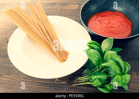 Vollkorn Spaghetti, Tomatensoße und Basilikum. Die grundlegenden Zutaten für eine diätetische und leckeres Gericht. Stockfoto