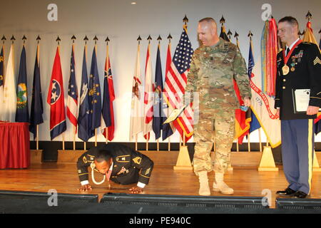 Sgt. 1. Klasse Marcus Mitchell des 21 Theater Sustainment Command führt Push-ups in light-hearted Sühnung für das Fallenlassen einer Münze während der Befehl Sgt. Maj. Rodney Rhoades, der 21 Theater Sustainment Command Senior Leader angeworben, und Sergeant Morales Club eingezogenes Sgt. Trevor J. Dodds Blick auf während der SMC Induktion Zeremonie am Turm Kaserne Theater hier Nov. 12 statt. (Foto: Staff Sgt. Christina J. Turnipseed, 18 Military Police Brigade Public Affairs) Stockfoto