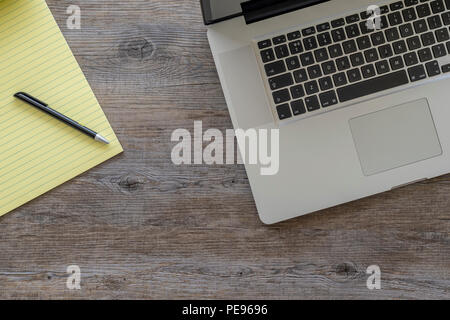 Flach, Holz- Tisch mit Laptop und einem gelben Legal Pad. Stockfoto