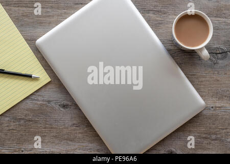 Flach, Holz- Tisch mit Laptop und gelb Rechtlicher Hinweis Pad. Stockfoto