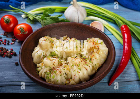 Manti in einem Ton Schüssel auf einem blauen Hintergrund aus Holz Stockfoto