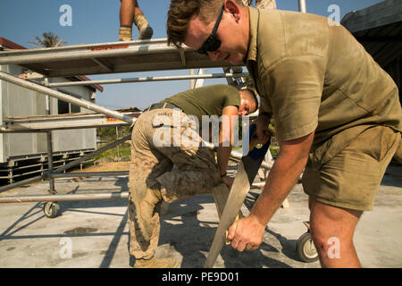 Australian Defence Force Pvt. Steven J. Jones, rechts, Sägen ein Stück Holz während des US Marine Lance Cpl. Kyle W. Bagley hält Sie während der Übung Harii Hamutuk 2015 stetig, am Hafen Hera Naval Base, in Hera, Timor-Leste, 26. Oktober 2015. Diese Übung konzentriert sich auf die Bereitstellung verbesserter Infrastruktur für die lokale Gemeinschaft durch Aufgaben wie vertikale Bau-, Holz Rahmenkonstruktion, Reparaturen an bestehenden Strukturen, die Dienstprogramme unterstützen, Verkabelung, eine Struktur für Strom, und Installieren von Leitungen. Jones, von Melbourne, Victoria, Australien, ist ein Zimmermann mit 1 Combat Engineer Reg Stockfoto