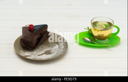 Scheibe der gourmet Schokolade Kuchen mit heißem Tee oder Kräutertee serviert auf einem weissem Holz Tisch mit Platz kopieren Stockfoto