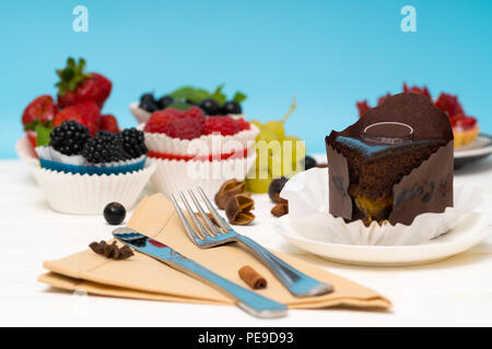 Verschiedene gourmet Desserts serviert auf einem weißen Tisch mit Schokolade Torte Kuchen und frisches Obst Kuchen mit Servietten und Besteck Stockfoto