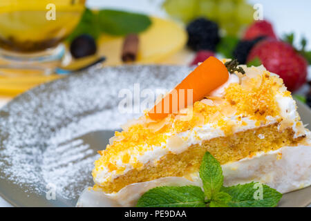 Scheibe der frisch gebackene gourmet Karottenkuchen mit bunten Gemüsegarnitur auf einem Teller serviert mit Puderzucker bestreuen und Umrisse einer Gabel Stockfoto