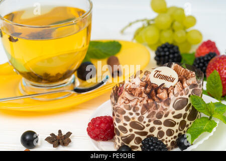 Elegante Portion Tiramisu Dessert garniert mit Minze und frischen Beeren mit würzigen Zitrone Tee serviert Stockfoto