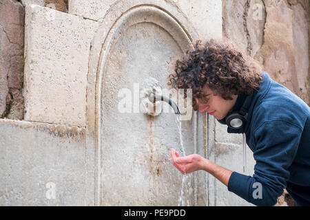 Junger Mann Getränke Wasser aus einem Brunnen Stockfoto