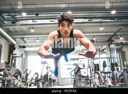 Hispanic junge passen Mann tun, Krafttraining, tut springen Push-ups im modernen Fitnessraum. Stockfoto