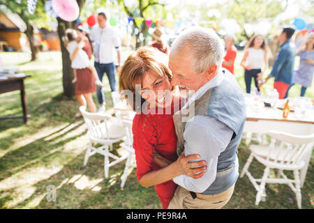 Ein älteres Paar tanzen auf einer Gartenparty außerhalb im Hinterhof. Stockfoto