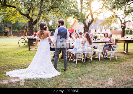 Braut und Bräutigam bei der Hand bei der Hochzeit Empfang draußen im Hinterhof. Stockfoto