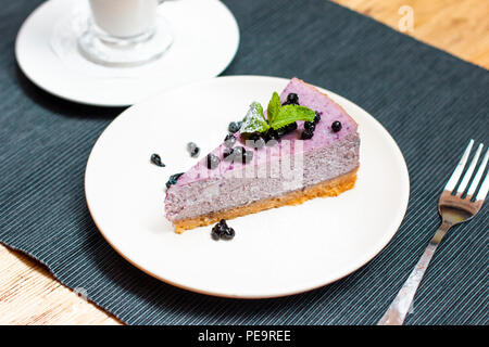 Heidelbeer Käsekuchen mit Beeren und Minze mit Kaffee Latte auf den Tisch Stockfoto