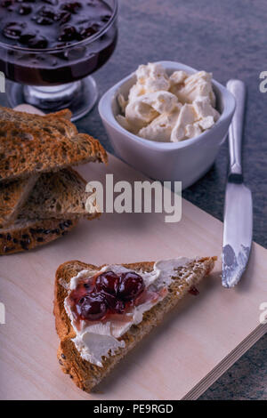 Close-up Toast mit Marmelade schwarze Johannisbeere und Frischkäse auf einer hölzernen Hintergrund Stockfoto