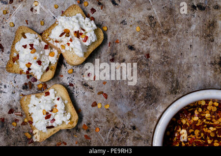 Flach Foto: miniatur Toast überbacken mit Käse und Paprika Flocken sitzen auf einem alten Metallwanne Hintergrund. Stockfoto