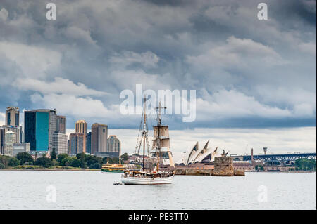 Eine wunderschöne Tall Ship Segeln in den Hafen von Sydney Australien, vorbei an einem fantastischen Skyline mit Wolkenkratzern und dem Sydney Opera House im Hintergrund. Stockfoto