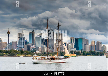 Eine wunderschöne Tall Ship Segeln in den Hafen von Sydney Australien, vorbei an einem fantastischen Skyline mit Wolkenkratzern im Hintergrund. Stockfoto