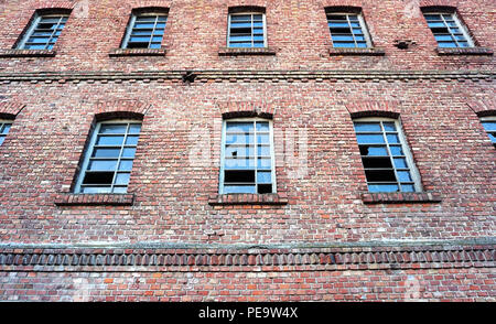 Industrielle verlassenen Gebäude Ruinen Fassade, Wand, aus rotem Backstein, Fenster mit Glasscherben auf der Fassade Oberfläche Stockfoto