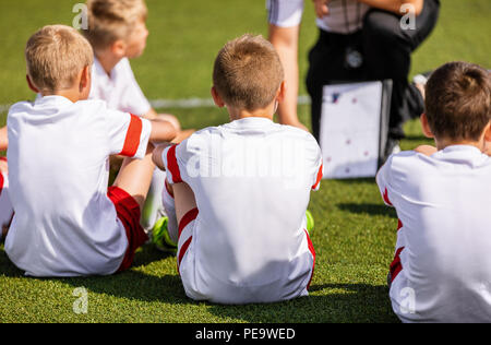 Fußball-Trainer coaching Kinder mit Taktik Strategie Whiteboard. Fußball-Trainer erklären match Taktiken zu Kinder Fußball Team. Jungen in einer Sportswear loo Stockfoto