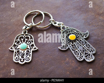 Zwei Schlüsselanhänger in Form von Fatima Hand auf braunem Hintergrund. Altes Symbol und traditionellen moderne touristische Souvenir von Tunesien. Stockfoto