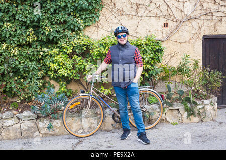 Mann in Helm und Brille bleiben Sie auf dem Fahrrad im Garten Stockfoto