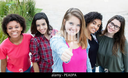 Blond kaukasische Frau, Daumen mit einer Gruppe von Freundinnen im Sommer Stockfoto