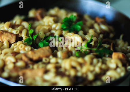 Nahaufnahme der Pasta mit Fleisch und Grüns in einer Pfanne bei blured Hintergrund Stockfoto
