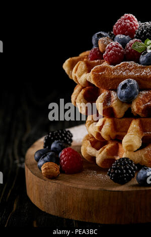 Nahaufnahme der leckere Belgische Waffeln mit Beeren auf Holz Schneidebrett auf Schwarz Stockfoto