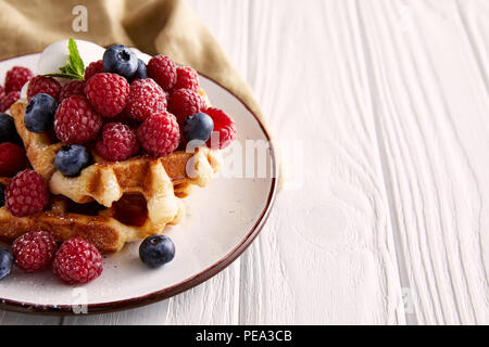 Nahaufnahme der leckere Belgische Waffeln auf Platte auf weiße Holztisch Stockfoto