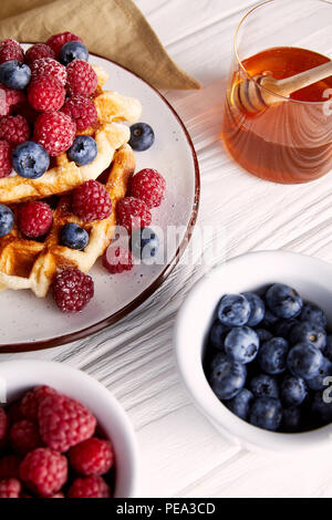 Nahaufnahme der köstliche belgische Waffeln mit Beeren und Honig auf weiße Holztisch Stockfoto