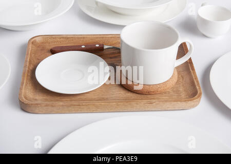 In der Nähe von Holz- fach, verschiedene Teller und Schüssel mit Schale am weißen Tisch Stockfoto