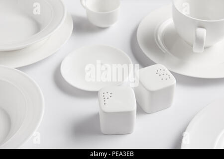 Selektiver Fokus der verschiedenen Teller, Tasse, Schüssel, Salzfass und Pfeffer caster am weißen Tisch Stockfoto