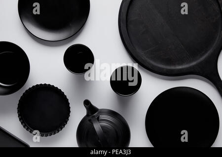 Blick von oben auf die schwarzen Teekanne, Teller, Schüssel, backen Teller und Tassen in der Nähe von Fach am weißen Tisch Stockfoto