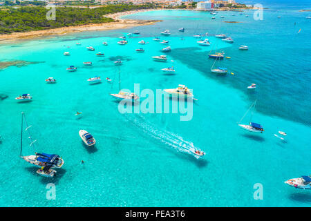 Boote und Yachten in transparenten Meer bei Sonnenaufgang auf Mallorca, Spanien. Luftaufnahme. Bunte Landschaft mit Marina Bay, azurblaues Wasser, Sandstrand. B Stockfoto