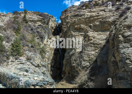 Ein kleiner Wasserfall in einem felsigen Berg im Himalaya an einem sonnigen Frühlingstag, Nepal. Stockfoto