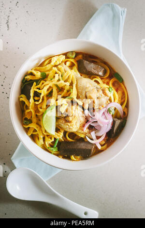 Curry Nudelsuppe (Khao soi) mit Kokosmilch, Northern Thai Küche, geringe Tiefenschärfe, Fokus auf Huhn. Stockfoto