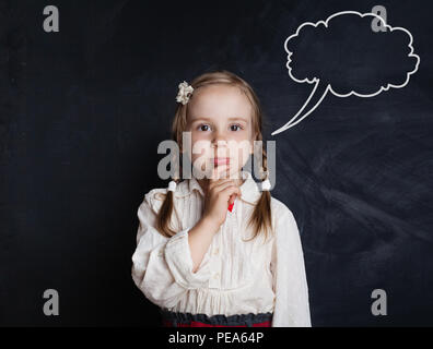 Denken kleines Mädchen gegen Rede wolken Kreidezeichnung auf blackboard Hintergrund. Cute nachdenkliches Kind Portrait Stockfoto