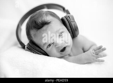 Neugeborenes Baby Hören von Musik über Kopfhörer auf einer Decke - glückliche Familie Momente Cute Stockfoto