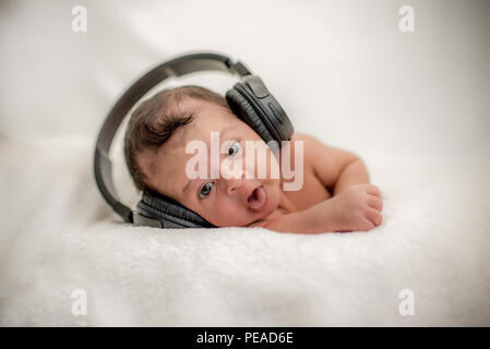 Neugeborenes Baby Hören von Musik über Kopfhörer auf einer Decke - glückliche Familie Momente Cute Stockfoto