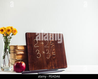 Vintage Books, alte Uhr, Bleistifte, roten Apfel und Tafel mit einem handschriftlich verfassten Inschrift auf einem Holz-, weißer Tisch. Nahaufnahme, isoliert. Zurück zu schoo Stockfoto