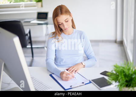 High Angle Shot der jungen Geschäftsfrau, Sitzen im Büro und dabei einige Schreibarbeit. Stockfoto